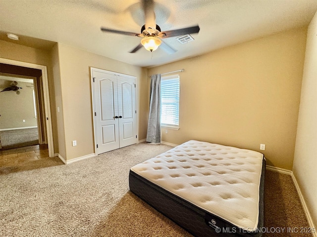 bedroom with carpet, visible vents, baseboards, ceiling fan, and a closet