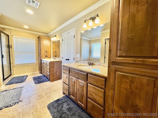 full bathroom with visible vents, two vanities, a stall shower, ornamental molding, and a sink