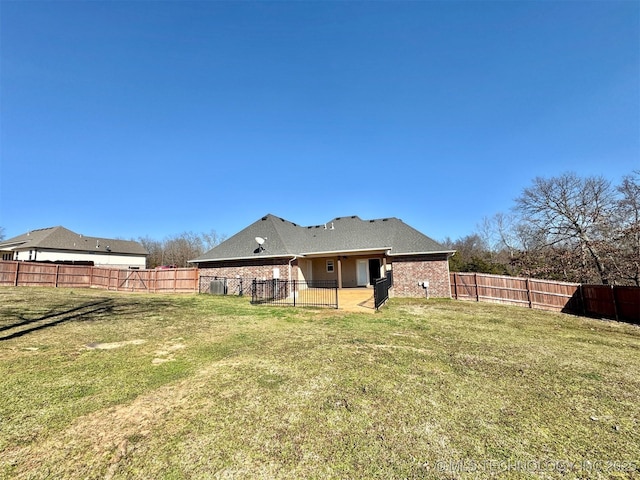 back of property with a yard, brick siding, a fenced backyard, and a patio area