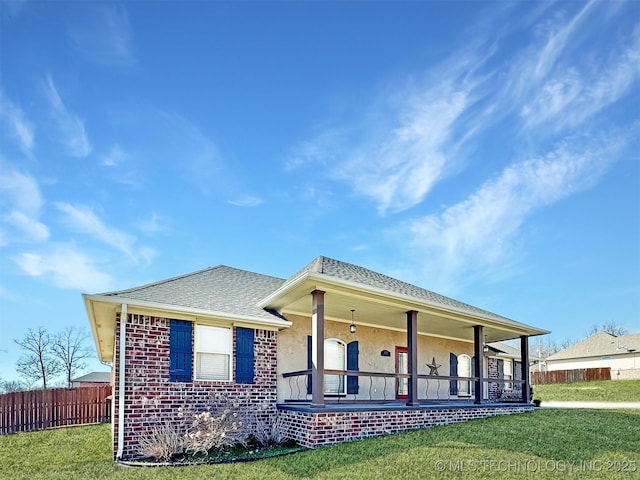 view of front of house featuring stucco siding, roof with shingles, a front yard, and fence