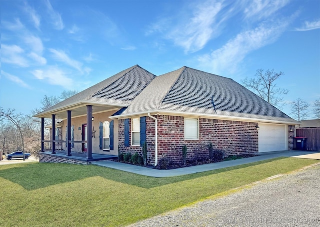 view of home's exterior featuring brick siding, a shingled roof, covered porch, a yard, and driveway