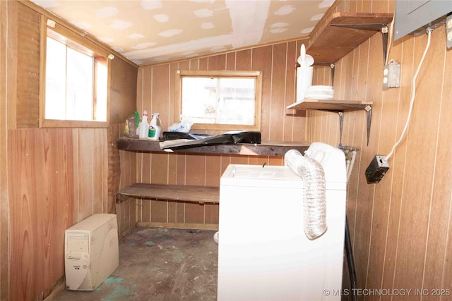 clothes washing area featuring a wealth of natural light, laundry area, wood walls, and washer / dryer