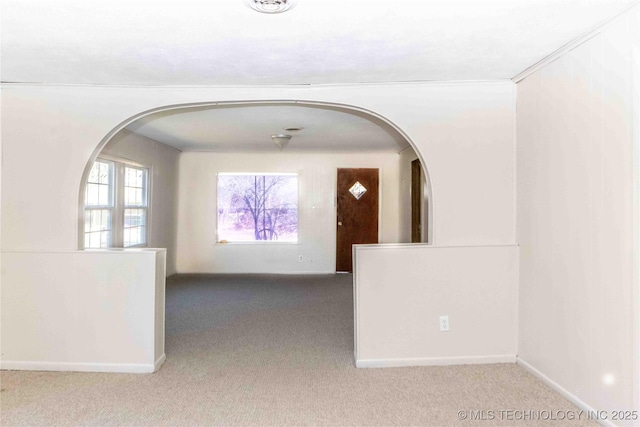 unfurnished room featuring baseboards, arched walkways, and carpet floors