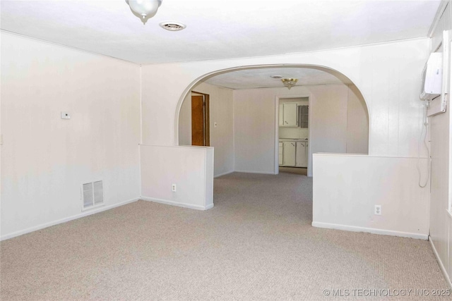empty room featuring visible vents, arched walkways, carpet, and baseboards