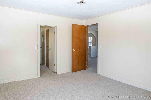 unfurnished room with visible vents, crown molding, baseboards, carpet, and arched walkways