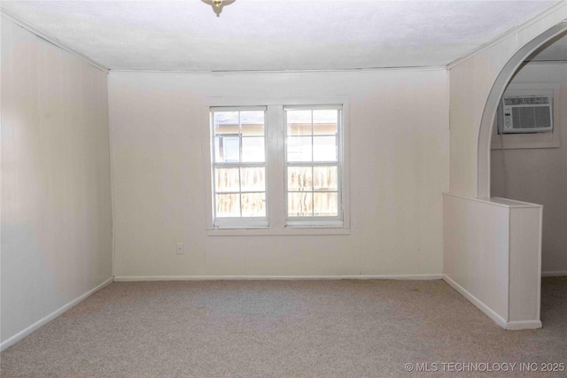 empty room featuring carpet flooring, an AC wall unit, and baseboards