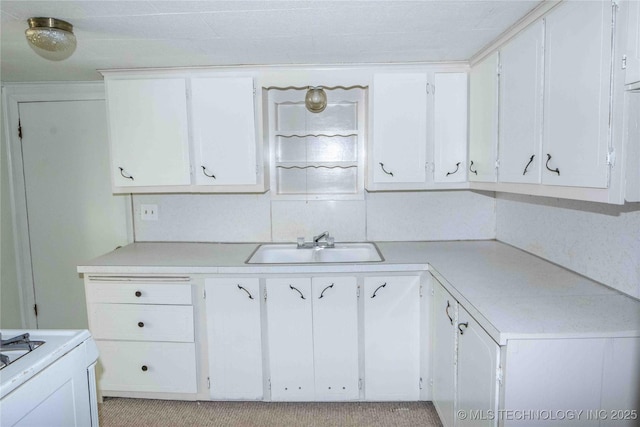 kitchen with white cabinets, light countertops, and a sink