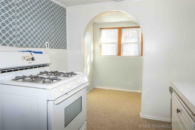 kitchen with ornamental molding, white gas range oven, carpet flooring, arched walkways, and white cabinets