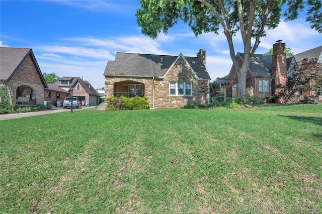 tudor home featuring a front lawn and a shingled roof