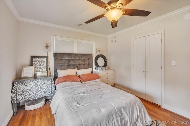 bedroom with visible vents, wood finished floors, baseboards, and ornamental molding