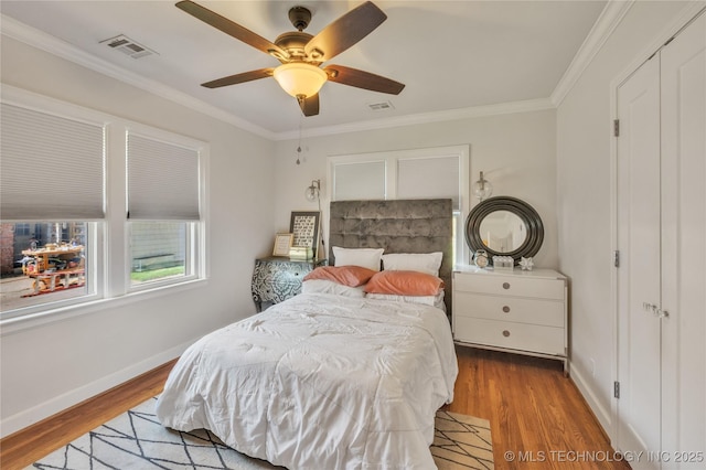 bedroom featuring visible vents, baseboards, wood finished floors, and crown molding