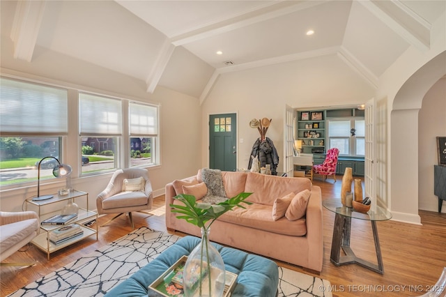 living area featuring baseboards, arched walkways, high vaulted ceiling, and wood finished floors