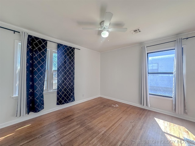 spare room featuring a ceiling fan, wood finished floors, visible vents, and baseboards