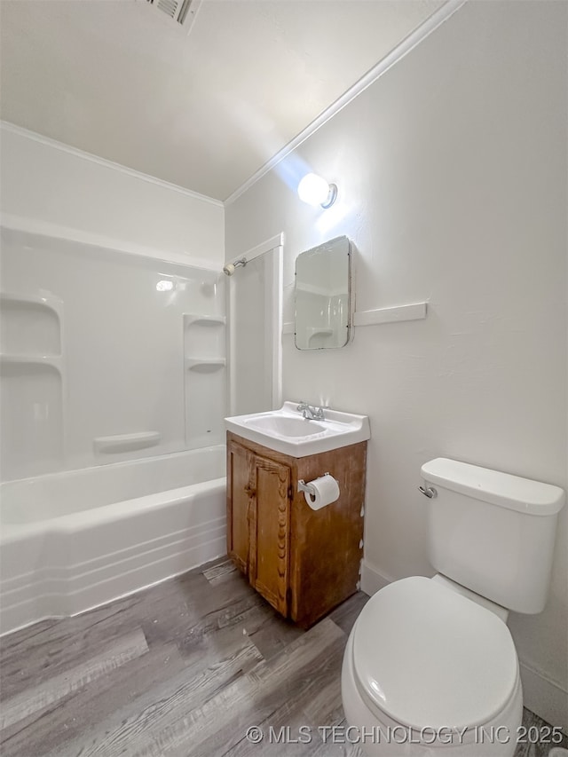 bathroom with toilet, ornamental molding, bathtub / shower combination, wood finished floors, and vanity