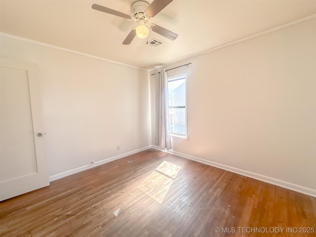 unfurnished room with visible vents, ornamental molding, a ceiling fan, wood finished floors, and baseboards