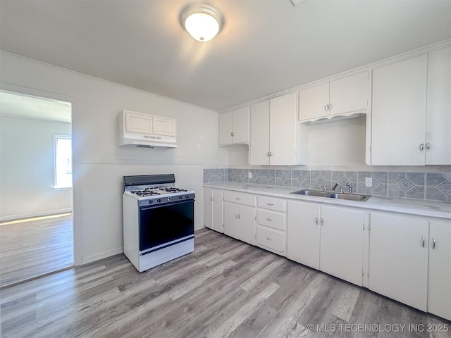 kitchen with a sink, decorative backsplash, white gas range, and light countertops