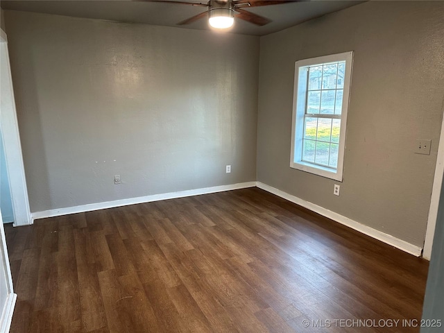 empty room featuring baseboards, ceiling fan, and dark wood-style flooring