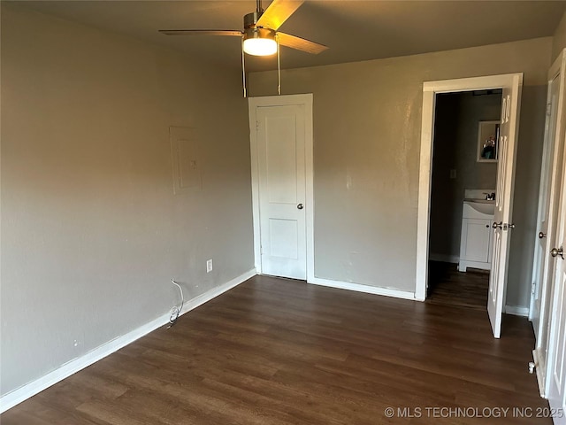 unfurnished bedroom with a sink, baseboards, dark wood-type flooring, and a ceiling fan