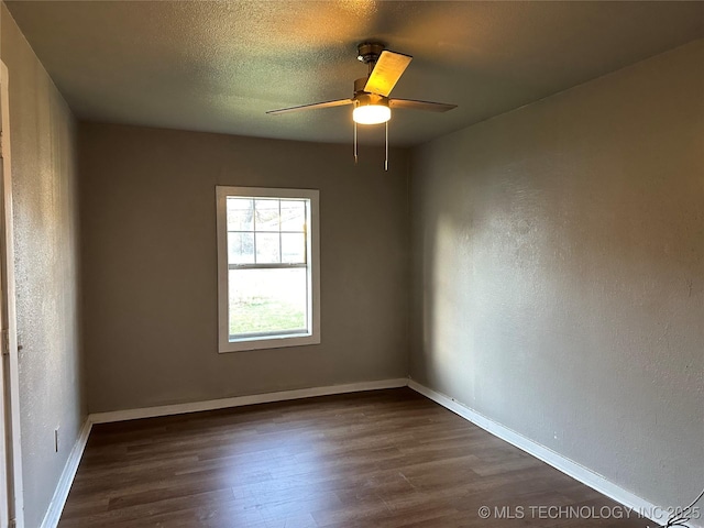 spare room with baseboards, dark wood-type flooring, ceiling fan, and a textured ceiling