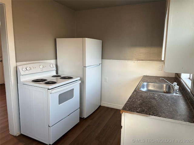 kitchen with a sink, white appliances, dark countertops, and dark wood-type flooring