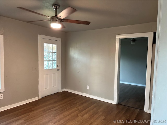 interior space featuring dark wood-type flooring, a ceiling fan, and baseboards