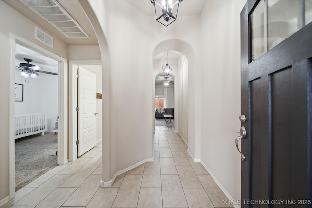 foyer featuring visible vents, radiator, light tile patterned flooring, arched walkways, and a ceiling fan