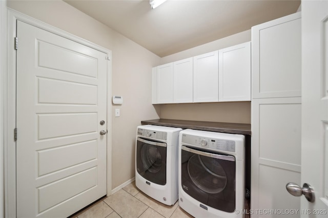 laundry room featuring washing machine and clothes dryer, light tile patterned floors, cabinet space, and baseboards