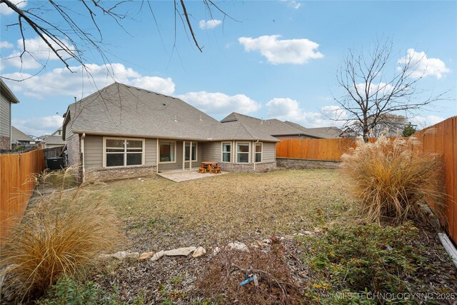 back of property with a fire pit, roof with shingles, a yard, a fenced backyard, and a patio