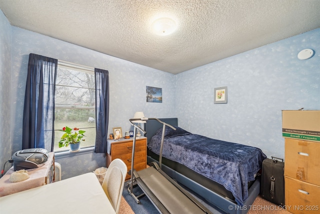 bedroom featuring wallpapered walls and a textured ceiling