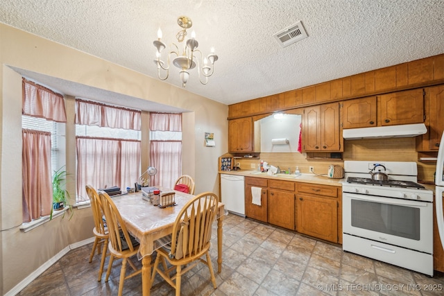 kitchen with visible vents, under cabinet range hood, light countertops, brown cabinetry, and white appliances