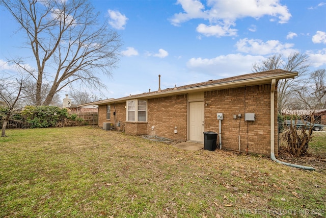 rear view of house with a lawn, central AC, brick siding, and fence