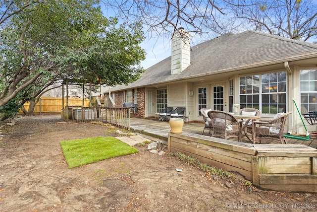 back of property with fence, a chimney, roof with shingles, and a wooden deck