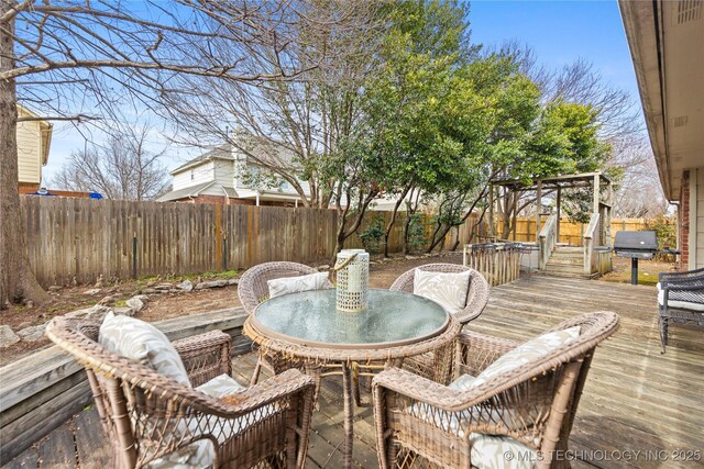 wooden deck featuring area for grilling, outdoor dining area, and a fenced backyard