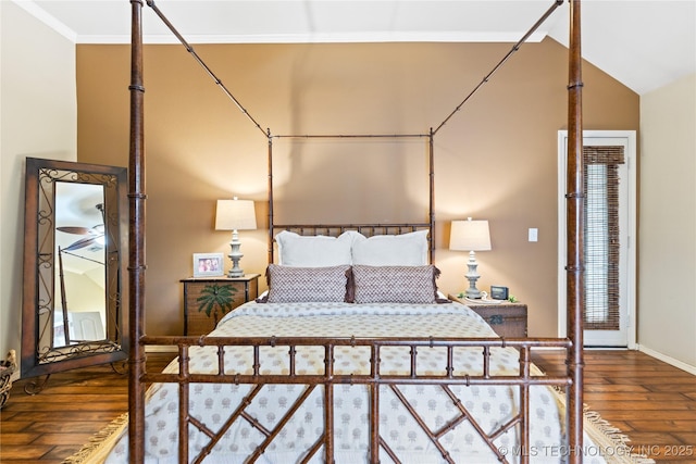 bedroom featuring baseboards, wood finished floors, vaulted ceiling, and ornamental molding