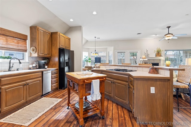 kitchen featuring a kitchen bar, a healthy amount of sunlight, stainless steel dishwasher, and black fridge