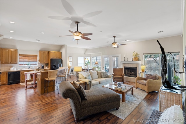 living area with visible vents, wood-type flooring, a healthy amount of sunlight, and a tiled fireplace