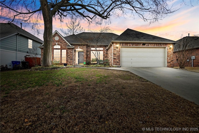 view of front of home with a lawn, roof with shingles, concrete driveway, a garage, and brick siding