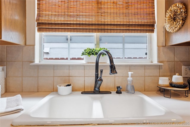 interior details featuring a sink, decorative backsplash, and light countertops