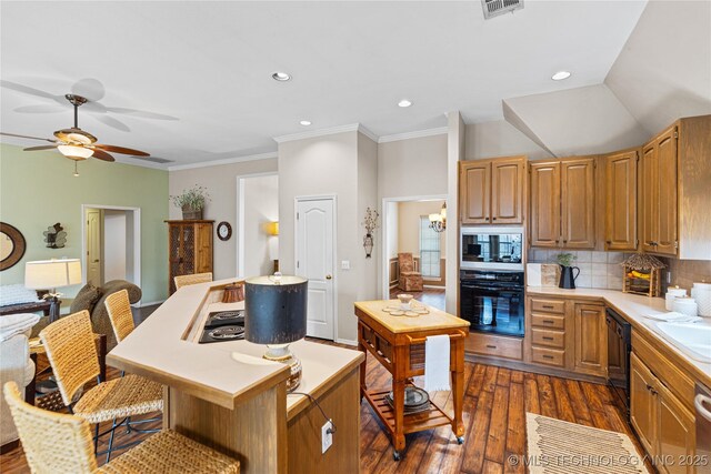 kitchen featuring a kitchen island, a breakfast bar, dark wood finished floors, light countertops, and tasteful backsplash