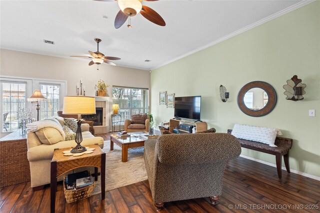 living area with baseboards, visible vents, dark wood finished floors, a fireplace with raised hearth, and ornamental molding