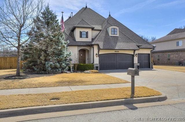 french country home featuring fence, roof with shingles, stucco siding, a garage, and driveway