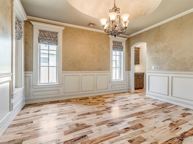 12491 S 105th Ave E, Bixby, OK 74008 - unfurnished dining area featuring arched walkways, light wood-style floors, wainscoting, a chandelier, and a decorative wall
