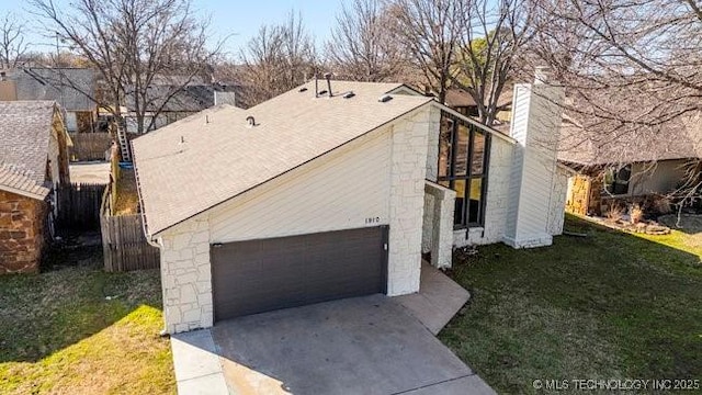 exterior space with a yard, a garage, concrete driveway, and a chimney