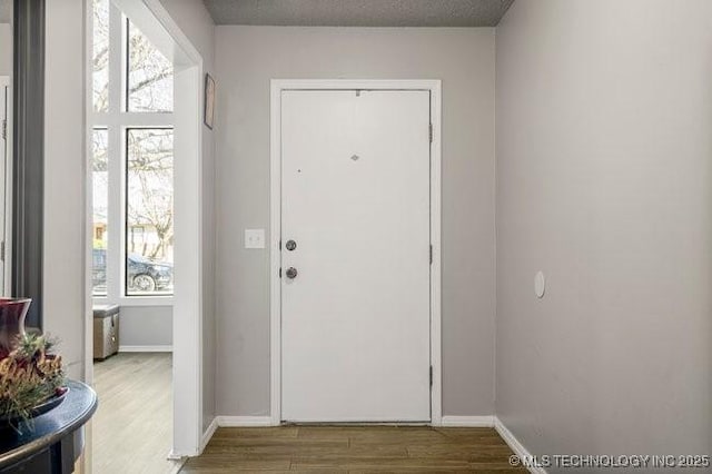 doorway to outside featuring baseboards and wood finished floors