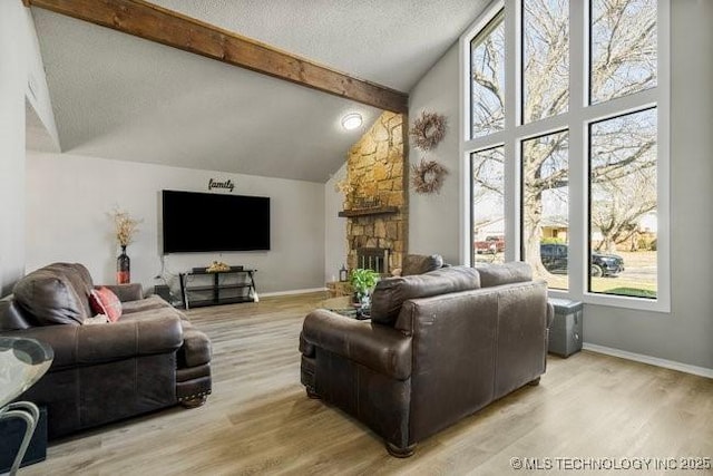 living room with light wood finished floors, beamed ceiling, a fireplace, and a textured ceiling