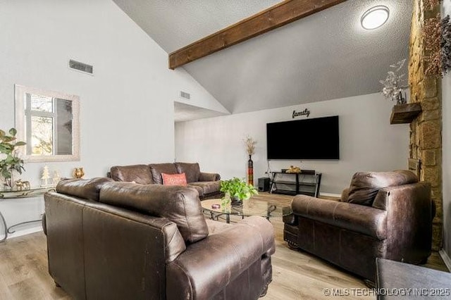 living area featuring beam ceiling, visible vents, light wood finished floors, and high vaulted ceiling