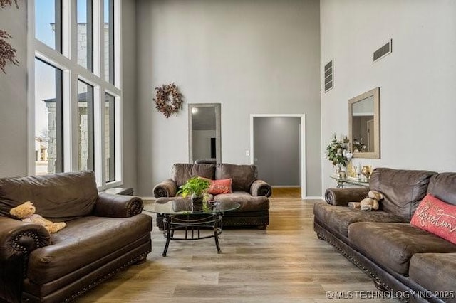 living area featuring a high ceiling, visible vents, and light wood-type flooring