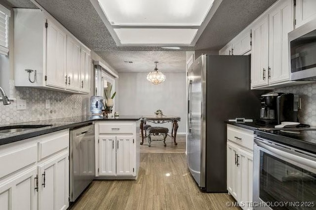 kitchen with a sink, light wood-type flooring, appliances with stainless steel finishes, and white cabinets