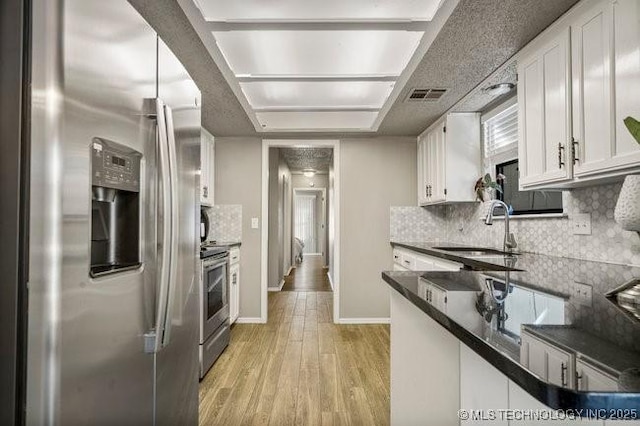 kitchen featuring visible vents, light wood-type flooring, appliances with stainless steel finishes, white cabinetry, and a sink