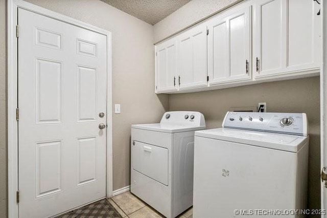 laundry room featuring light tile patterned flooring, cabinet space, a textured ceiling, and separate washer and dryer